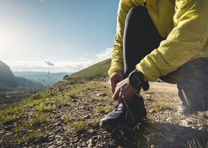 山中で靴紐を結び直しているトレイルランナー