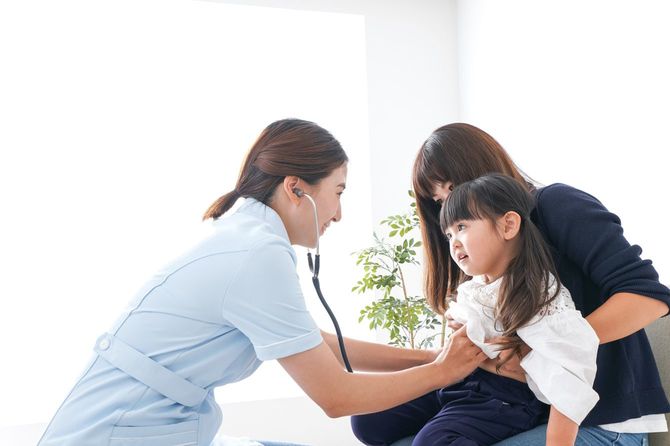 小さい女の子を診察する小児科医の女性