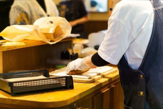 明太フランスを手際よくカットするスタッフ