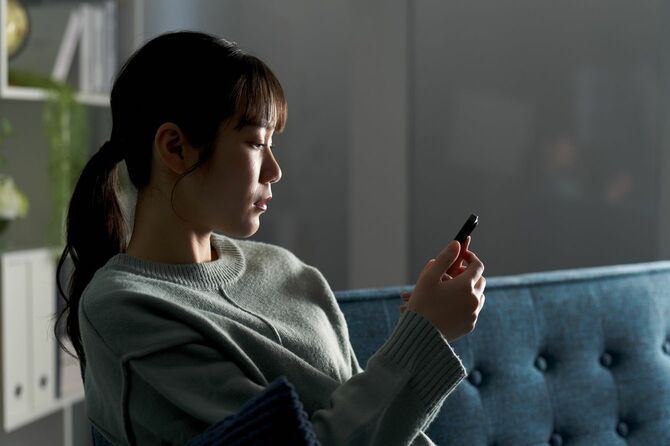 スマホを憂鬱な表情で見つめている女性