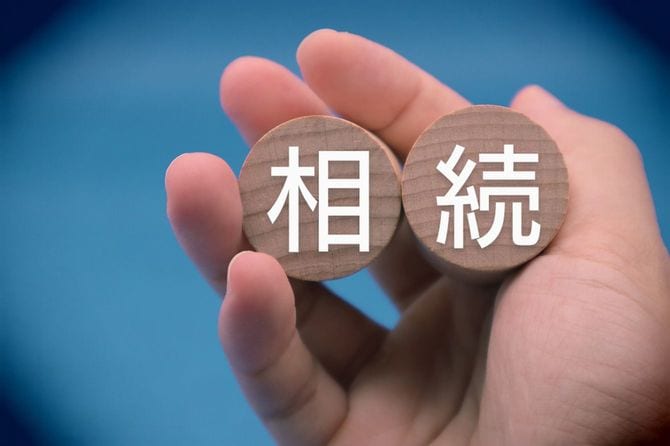 「相続」と書かれたブロックを持つ人の手