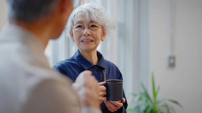 コーヒーを飲みながら会話するシニアビジネスマンとシニアビジネスウーマン
