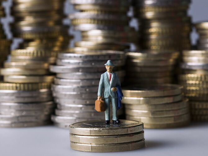 コインの山の上に立っているミニチュアフィギュア