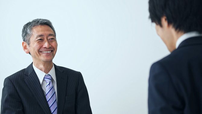 笑顔のシニア男性にあいさつする若い男性