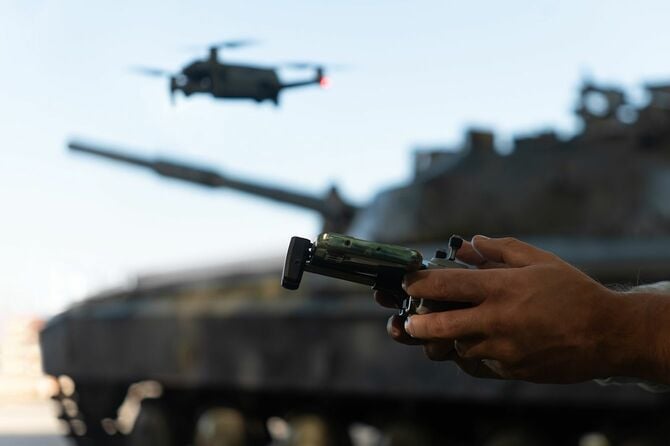 銃を持つ手の背景に戦車とドローン