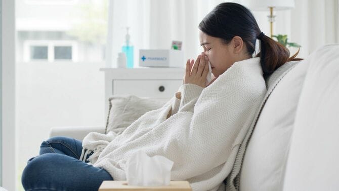 ソファに座って鼻をかむ女性