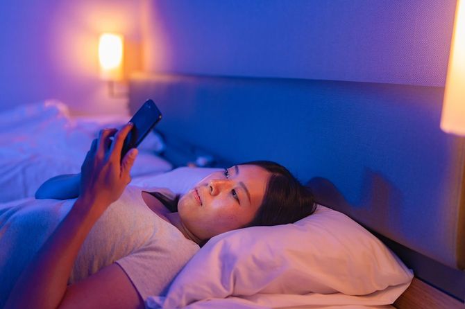 寝る前にベッドでスマホを見ている女性