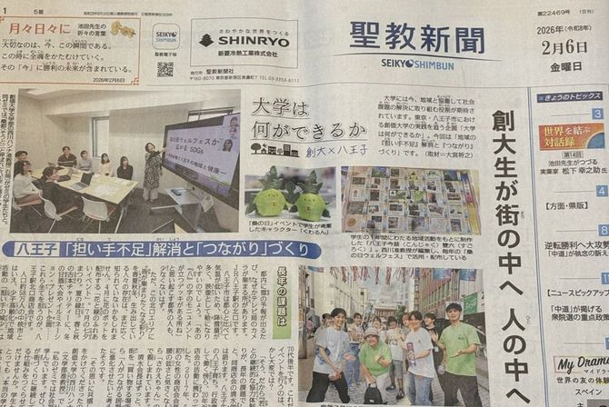 2月6日付の聖教新聞一面の写真。創価大学の学生の活動を紹介した普通の記事に見えるが、写真左側には「八王子」の文字が。2面でも八王子に関する記事が続き、紙面左側には、「八王子で」ではなく「八王子と」の思いで、という見出しが躍っている