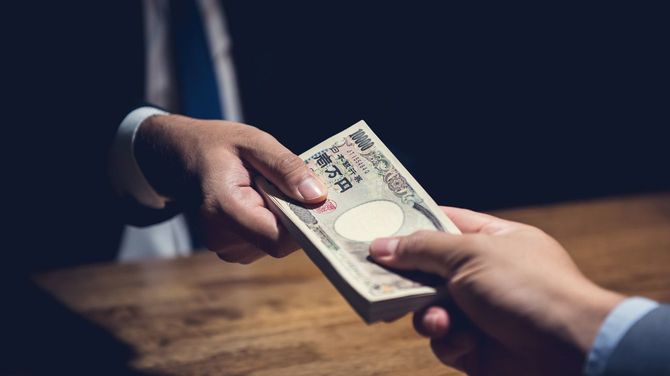 暗い部屋で札束を渡す男性の手元