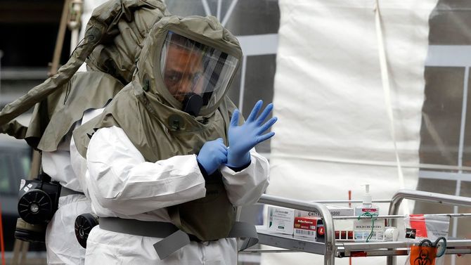 保護具を着用した医療従事者が、COVID-19試験を実施する前に手袋を調整する=2020年4月28日、マサチューセッツ州サマービルの病院の駐車場にある試験場