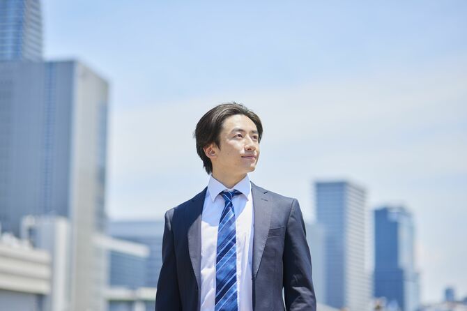 ビジネス街で遠くを見つめるスーツ姿の若いビジネスマン