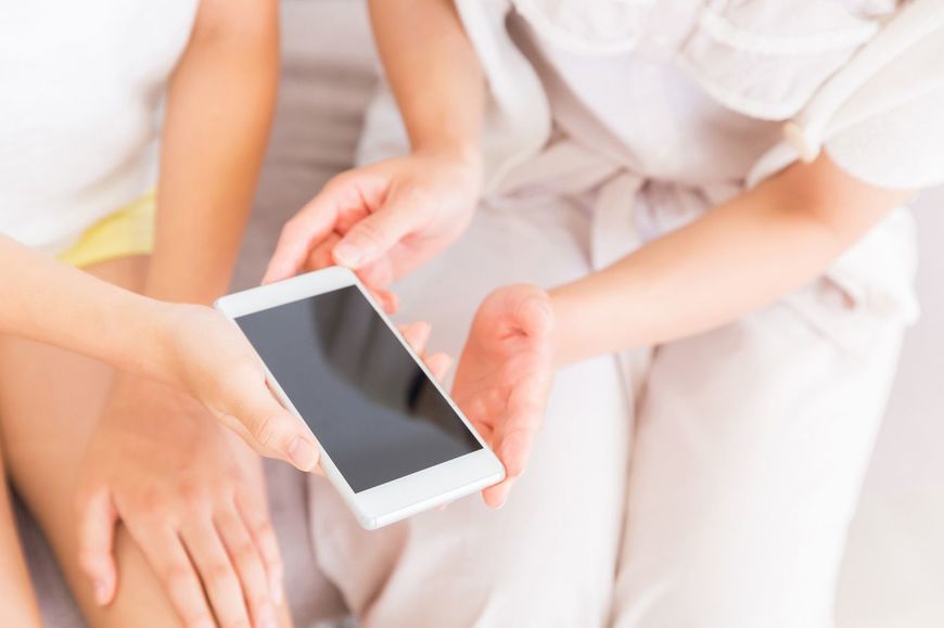 スマートフォンを持つ親と娘