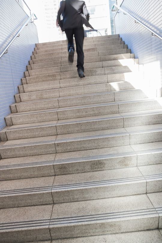 階段を駆け上がるスーツ着用の男性