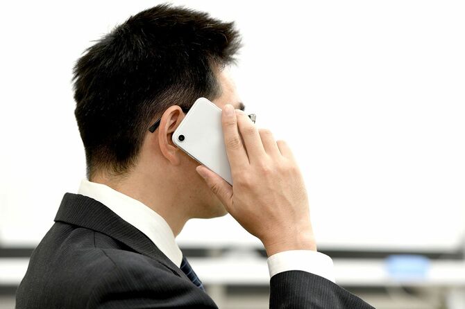 携帯電話で電話をかけるスーツ姿のビジネスマン