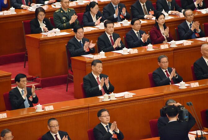 2024年3月11日、北京で開かれた中国の全国人民代表大会（全人代）の閉幕式で、議案可決後に拍手する習近平国家主席（中央）