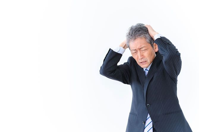 頭を抱える中年の男性