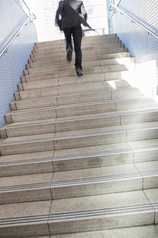 階段を駆け上がるスーツ着用の男性