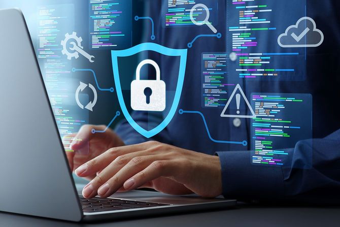 パソコンを操作する手元と、ネットワークセキュリティをイメージした南京錠などのグラフィック