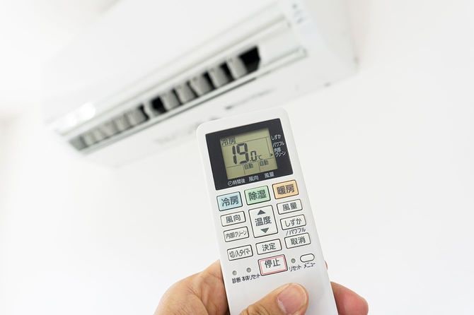 リモコンでエアコンの温度を19度に設定する人の手元