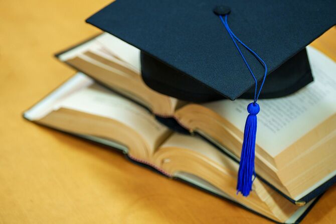 本の上に置かれた大学の卒業式でかぶる帽子