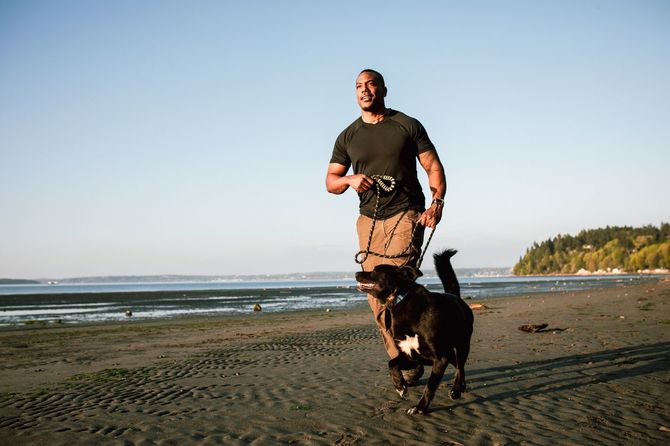犬とビーチで走る大人の男