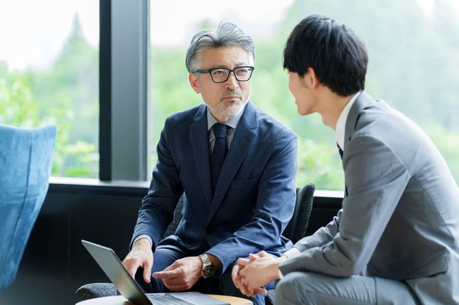 若いビジネスマンと話をする中年ビジネスマン
