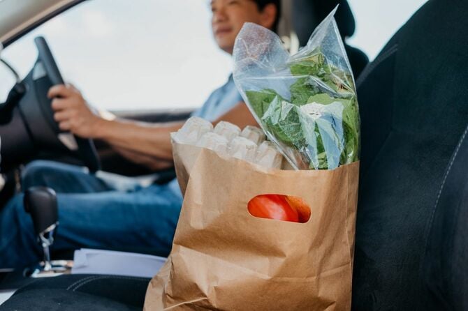 買い物袋を助手席に置いて運転するドライバー