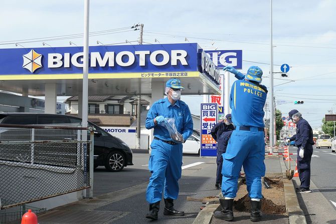 ビッグモーター平塚四之宮店前で土壌を採取する神奈川県警の捜査員＝2023年8月30日、同県平塚市