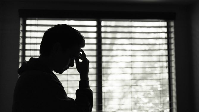 暗い部屋でストレスを感じる男性