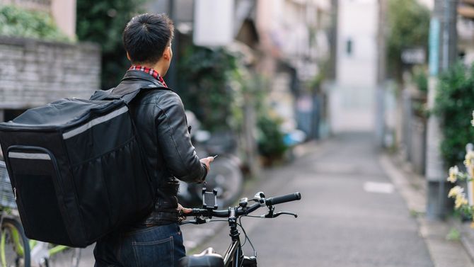 該当する住所を探している自転車配達員の男性