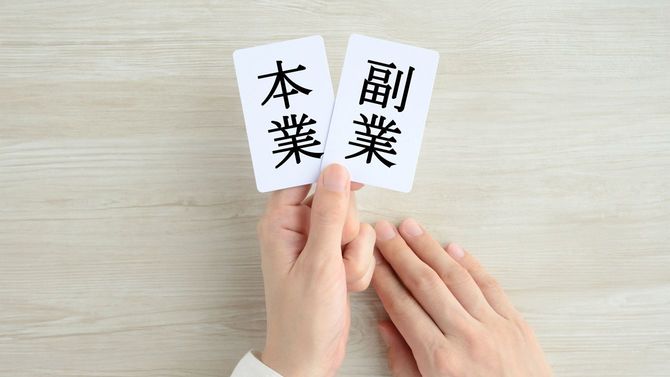 本業と副業のカードを持つ女性の手