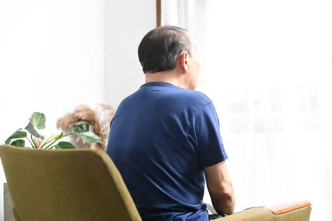 椅子に座って窓の外を見ている高齢者