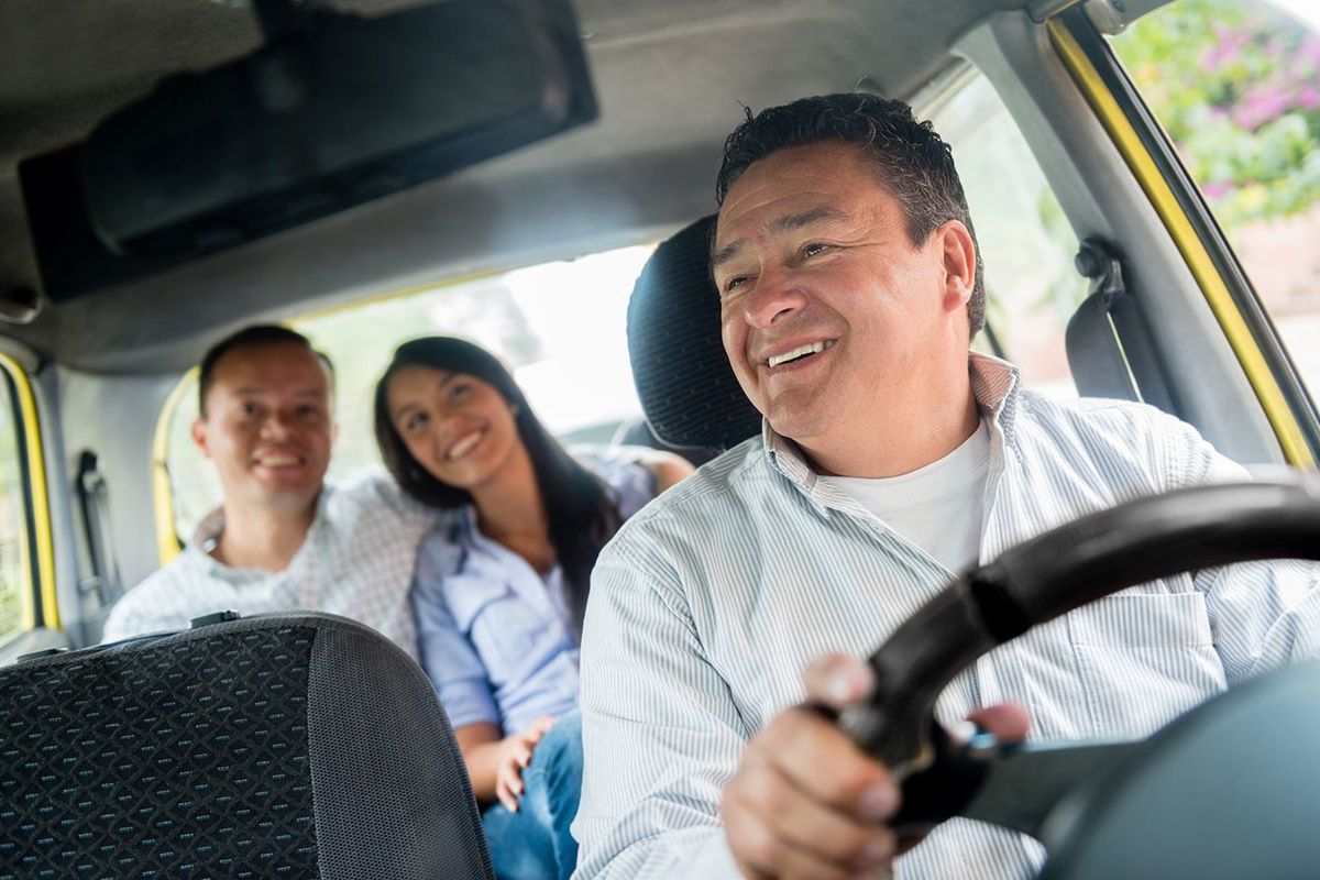 乗客のカップルを輸送する幸せなタクシー運転手