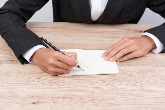 机の上に置かれた文書に署名する人