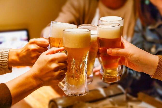 居酒屋で乾杯する多くの人々の手とジョッキのビール
