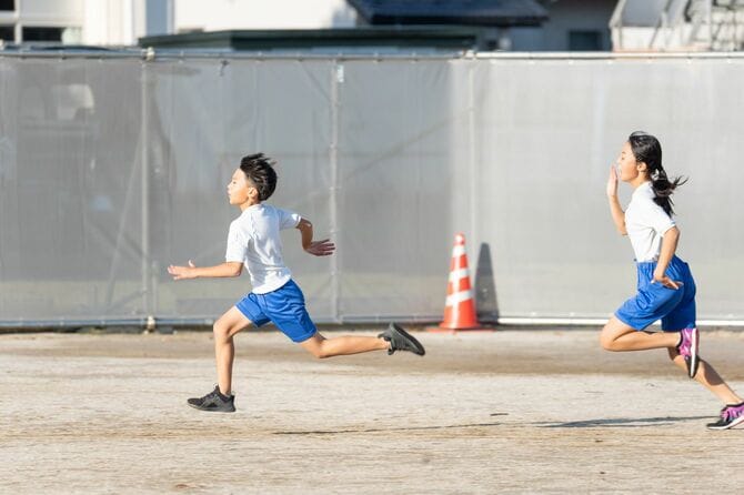 学校のグラウンドを走る小学生