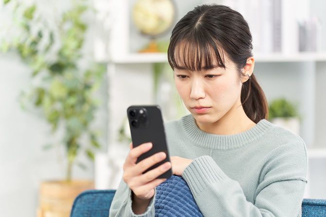 真剣な表情でスマホを見つめる女性