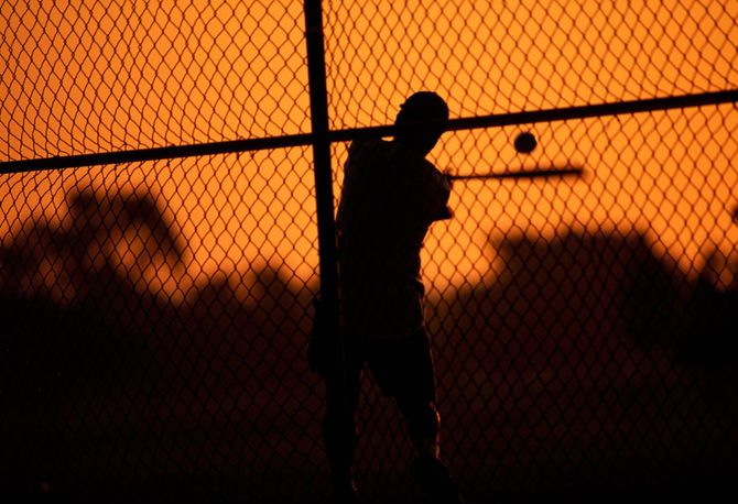 ボールをバットで打つ野球選手のシルエット