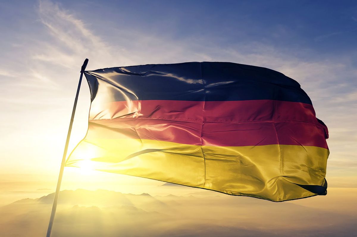 トップの日の出霧霧に手を振る旗竿織布のドイツ国旗