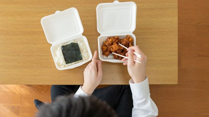 自宅でテイクアウトした唐揚げ弁当を食べるビジネスマン