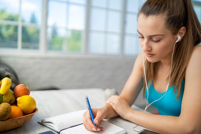 イヤホンをしてノートに書き込む女性