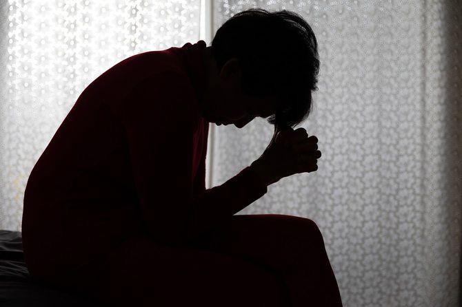 部屋でうなだれて座っている女性のシルエット