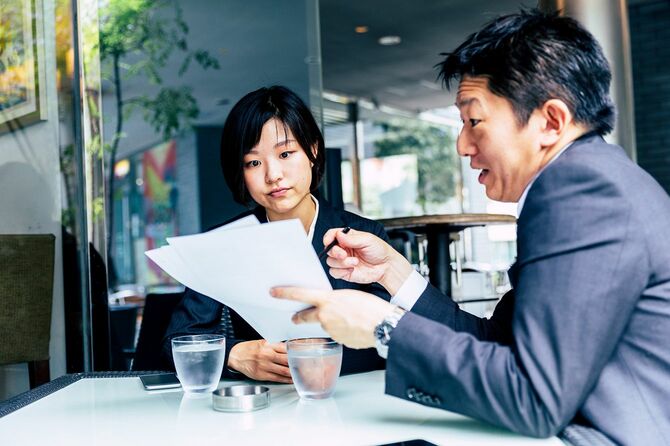 資料を見ながら女性に話をする男性