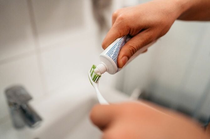歯ブラシに歯磨き粉を塗る手