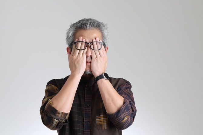 手で目を覆う男性