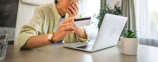 ノートパソコンで明細を確認して驚いている女性