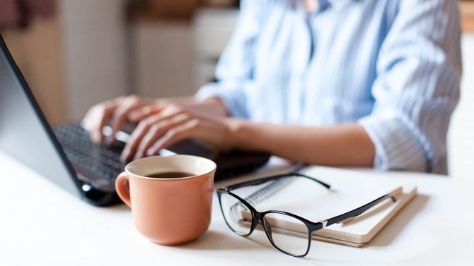 手元にマグカップを置き、ノートパソコンで自宅からリモート作業
