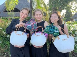 社員2人に囲まれ自社製品を持つ河野さん（中央）