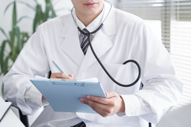 患者を診察する日本人男性医師