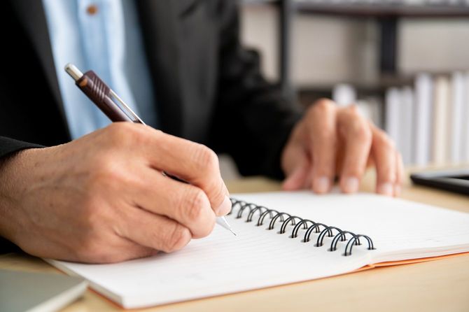 ノートにメモをとる男性の手元